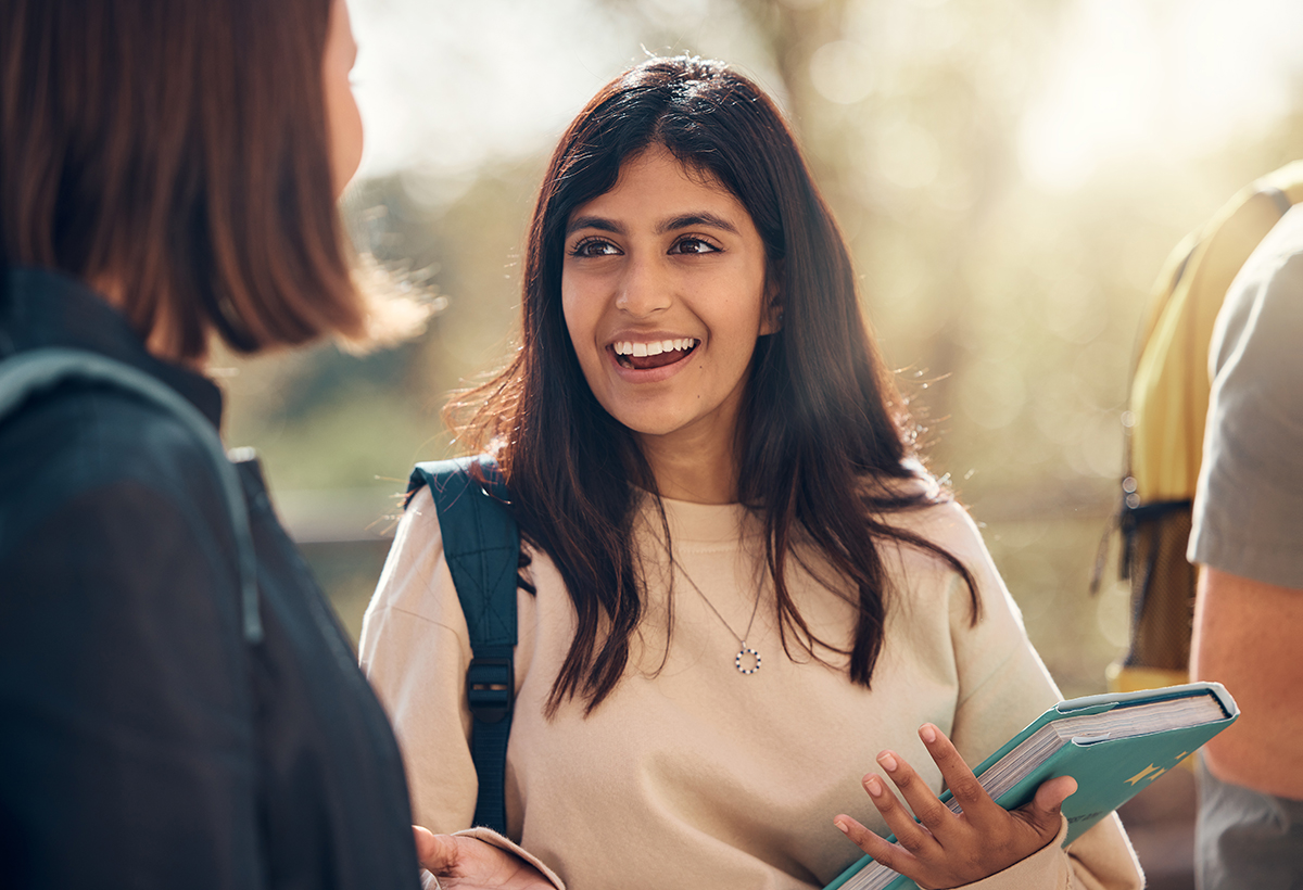 A woman holding a book and talking to a friend