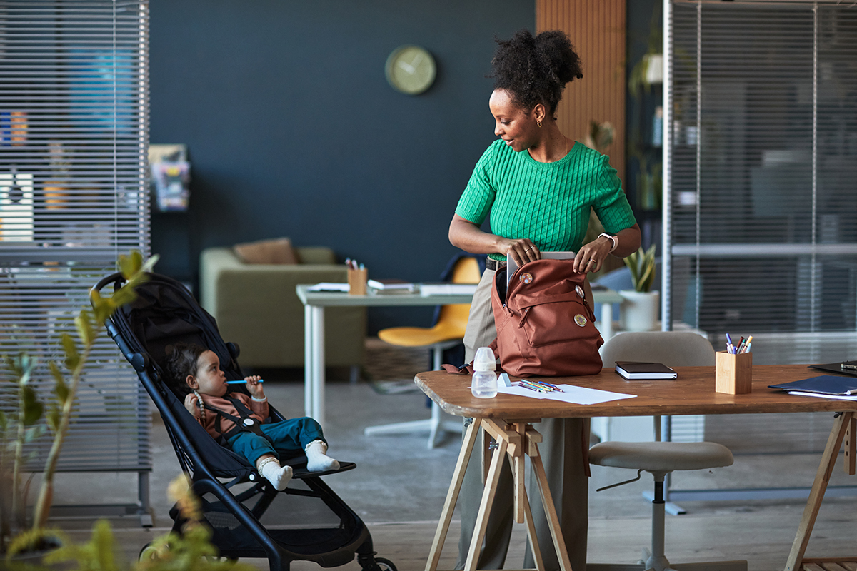 A woman packing a bag and looking at a child in a stroller